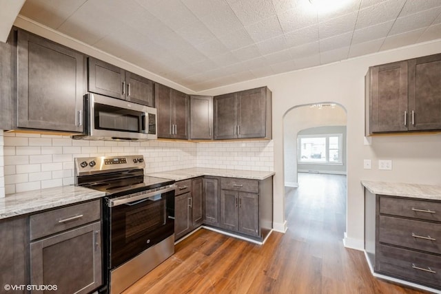 kitchen with light stone countertops, dark brown cabinets, and appliances with stainless steel finishes