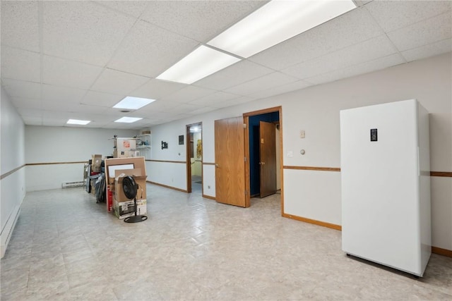 basement with white refrigerator and a paneled ceiling