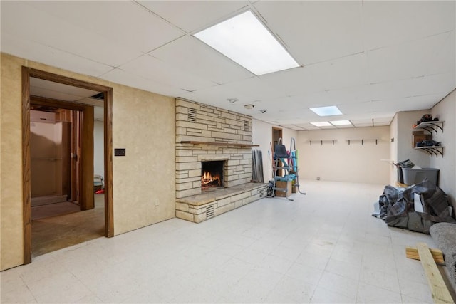 basement with a stone fireplace and a drop ceiling