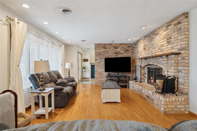 living room featuring light wood-type flooring and a brick fireplace