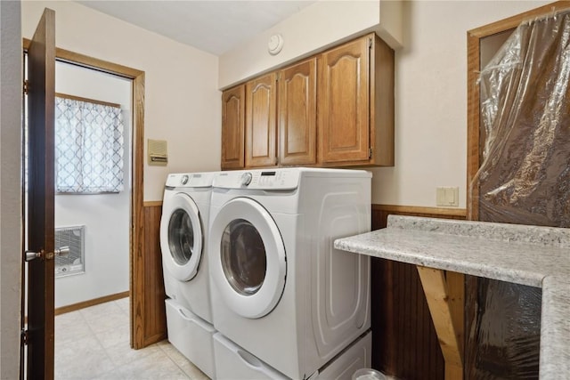 clothes washing area with separate washer and dryer, wood walls, heating unit, and cabinets