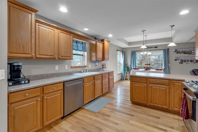 kitchen featuring hanging light fixtures, light hardwood / wood-style flooring, appliances with stainless steel finishes, a tray ceiling, and a chandelier