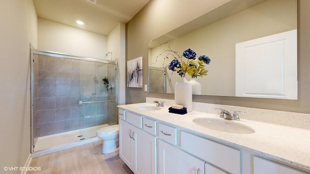 bathroom with hardwood / wood-style floors, vanity, toilet, and a shower with door