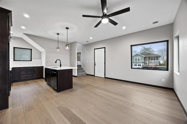 kitchen with pendant lighting, a kitchen island with sink, sink, ceiling fan, and light wood-type flooring