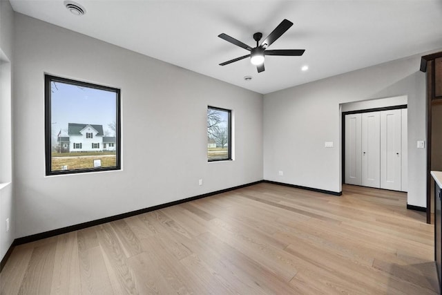 unfurnished bedroom with ceiling fan, light wood-type flooring, and multiple windows