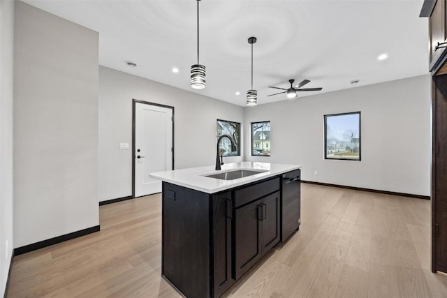 kitchen featuring sink, dishwasher, pendant lighting, light hardwood / wood-style floors, and a kitchen island with sink