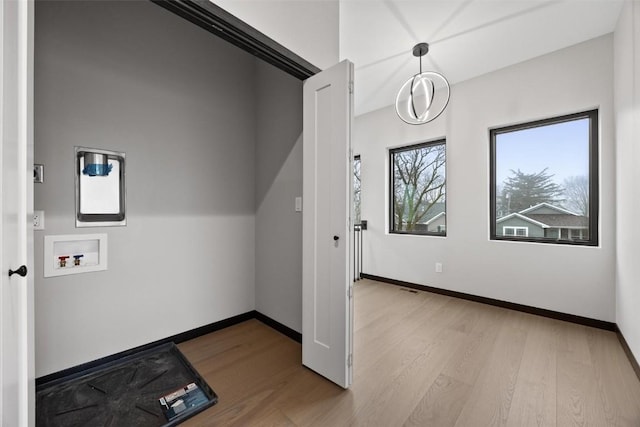 laundry room with washer hookup, light hardwood / wood-style floors, and a chandelier