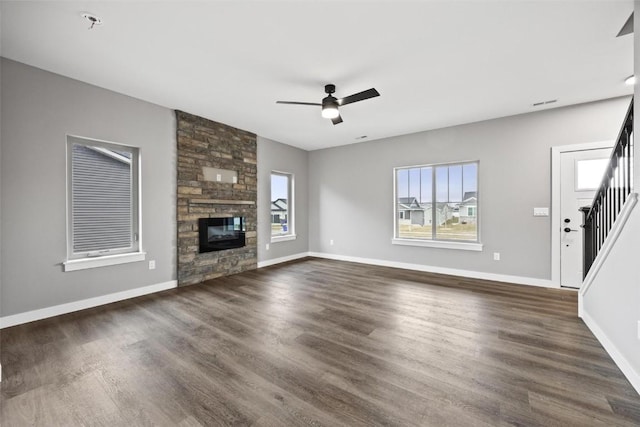 unfurnished living room featuring ceiling fan, a fireplace, and dark wood-type flooring