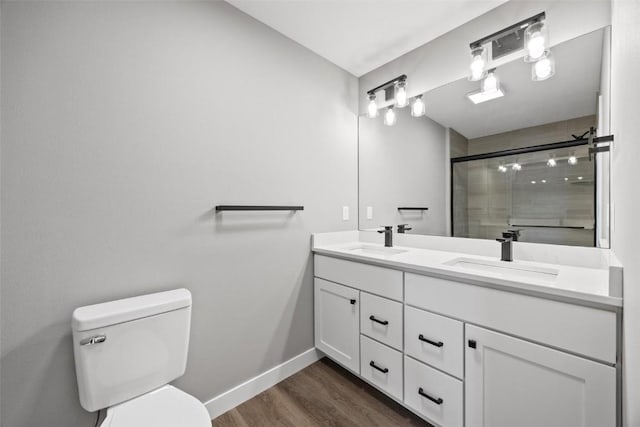 bathroom featuring a shower with door, vanity, hardwood / wood-style floors, and toilet