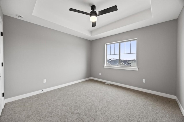 unfurnished room with a raised ceiling, ceiling fan, and carpet floors