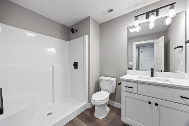 bathroom featuring a shower, hardwood / wood-style floors, vanity, and toilet