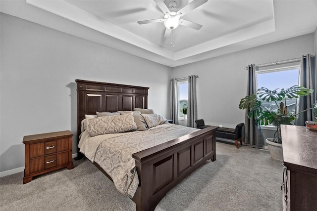 carpeted bedroom featuring ceiling fan and a tray ceiling