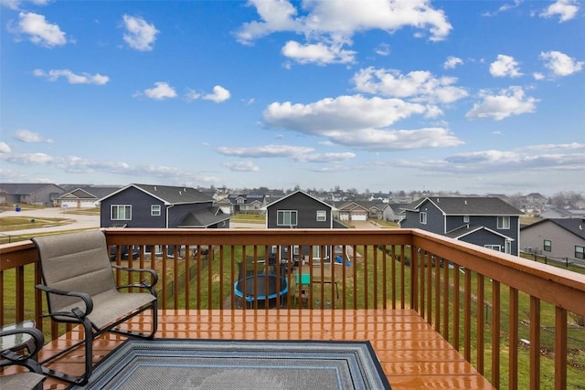 wooden terrace with a trampoline and a yard