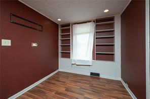 empty room with built in shelves and hardwood / wood-style floors