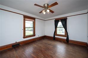 spare room with dark hardwood / wood-style flooring, ceiling fan, and a healthy amount of sunlight