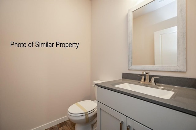 bathroom with hardwood / wood-style flooring, vanity, and toilet