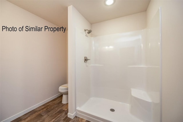 bathroom with hardwood / wood-style flooring, toilet, and a shower