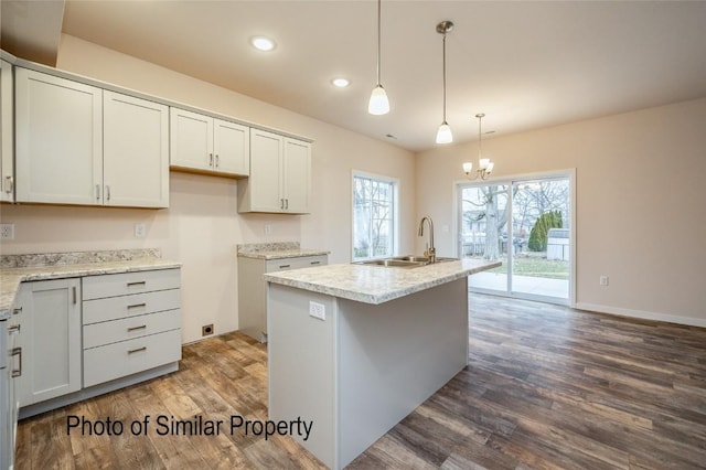 kitchen with white cabinets, pendant lighting, a kitchen island with sink, and sink