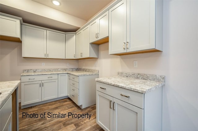 kitchen featuring white cabinetry, light stone counters, and dark wood-type flooring