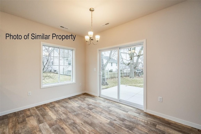 unfurnished dining area featuring hardwood / wood-style flooring and an inviting chandelier