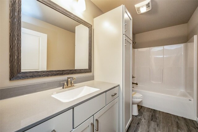 full bathroom with toilet, vanity, wood-type flooring, and washtub / shower combination