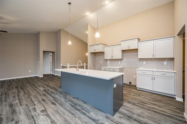 kitchen featuring white cabinetry, high vaulted ceiling, an island with sink, and decorative light fixtures