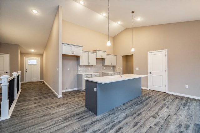 kitchen with white cabinetry, hanging light fixtures, high vaulted ceiling, backsplash, and a kitchen island with sink