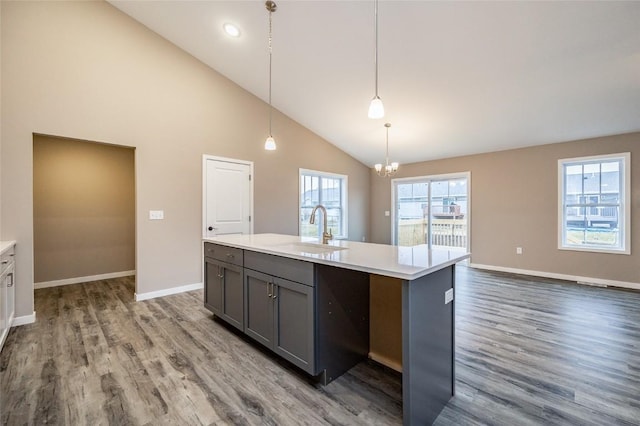 kitchen with a kitchen island with sink, sink, decorative light fixtures, high vaulted ceiling, and hardwood / wood-style floors