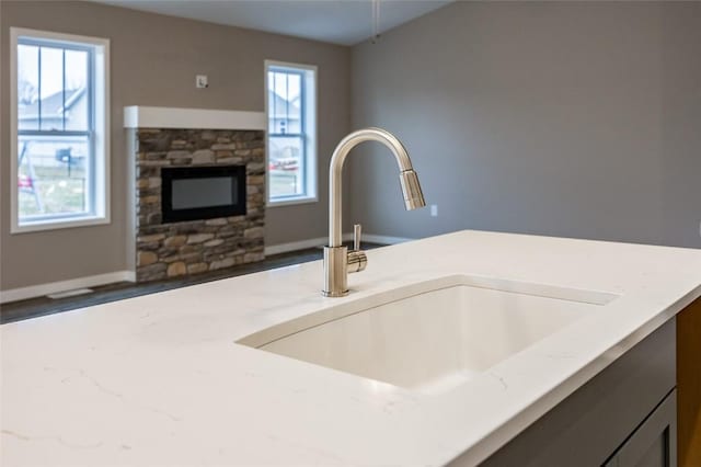 details with a fireplace, light stone countertops, and sink