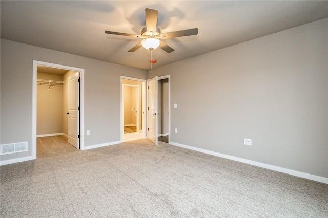 unfurnished bedroom with ceiling fan, light colored carpet, a spacious closet, and a closet