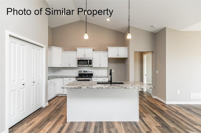 kitchen with stainless steel appliances, backsplash, pendant lighting, a kitchen island with sink, and white cabinets