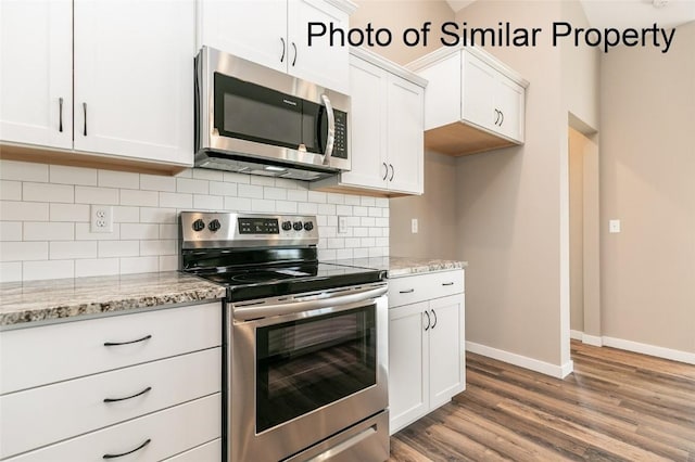 kitchen with white cabinets, wood-type flooring, light stone countertops, and stainless steel appliances