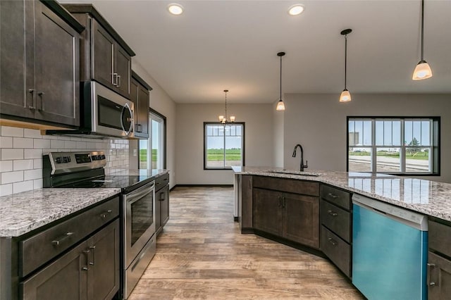 kitchen featuring decorative light fixtures, stainless steel appliances, dark brown cabinets, and sink