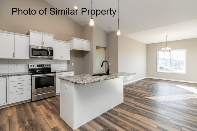 kitchen featuring appliances with stainless steel finishes, decorative light fixtures, a kitchen island with sink, and sink