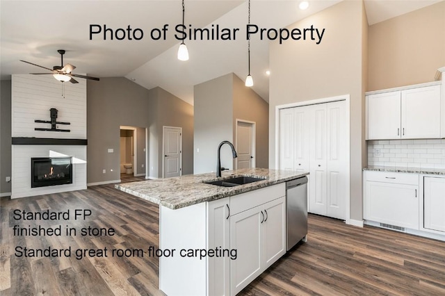 kitchen featuring pendant lighting, a kitchen island with sink, stainless steel dishwasher, light stone countertops, and white cabinetry