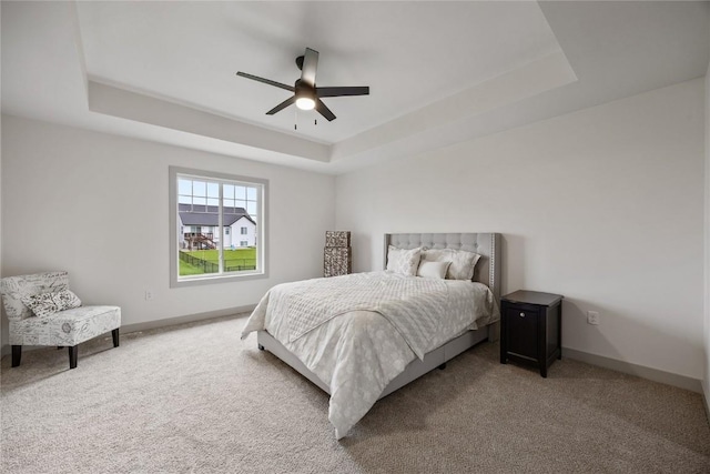 carpeted bedroom with baseboards, a ceiling fan, and a tray ceiling