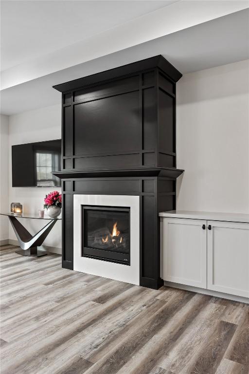 details with a glass covered fireplace and wood finished floors
