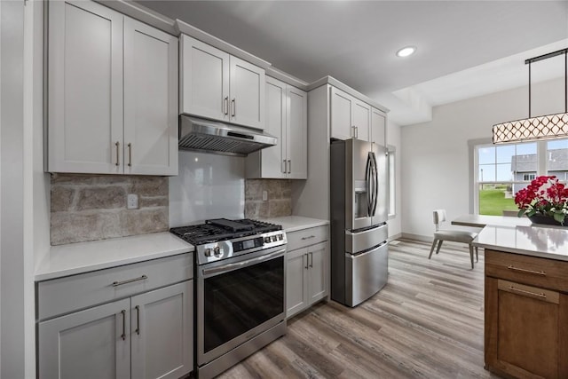kitchen with tasteful backsplash, light countertops, under cabinet range hood, stainless steel appliances, and recessed lighting