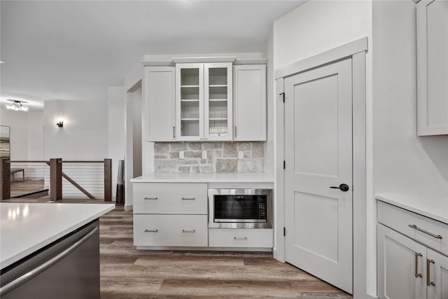kitchen featuring white cabinets, stainless steel appliances, decorative backsplash, and light countertops