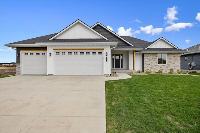 view of front of house featuring board and batten siding, driveway, a front lawn, an attached garage, and stone siding
