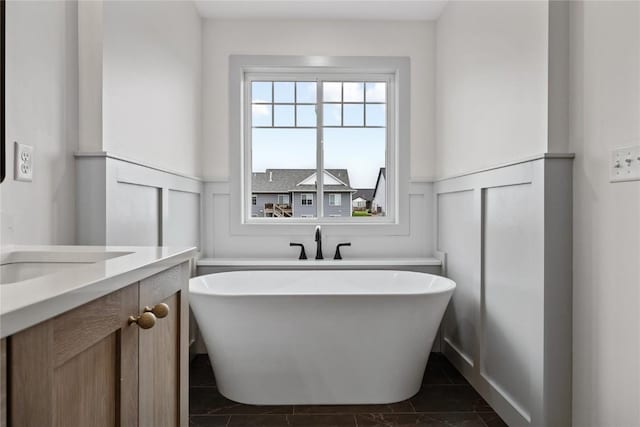 bathroom with tile patterned floors, a freestanding bath, a wainscoted wall, and a decorative wall
