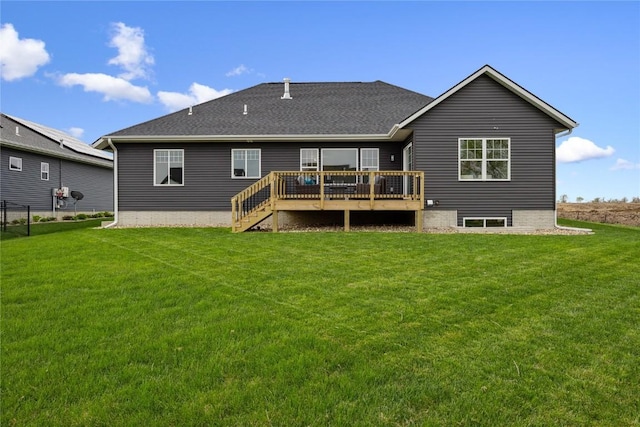 rear view of property featuring a lawn, fence, a shingled roof, and a deck