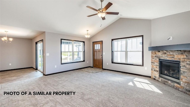 unfurnished living room with a stone fireplace, lofted ceiling, a healthy amount of sunlight, and ceiling fan with notable chandelier