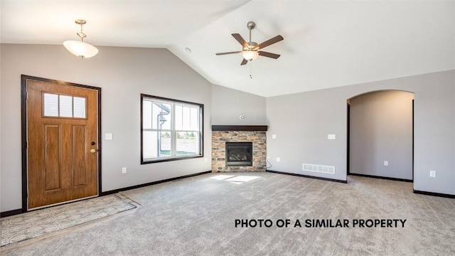 unfurnished living room featuring ceiling fan, a stone fireplace, lofted ceiling, and light carpet