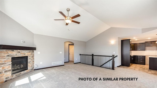 unfurnished living room with a fireplace, light colored carpet, vaulted ceiling, and ceiling fan