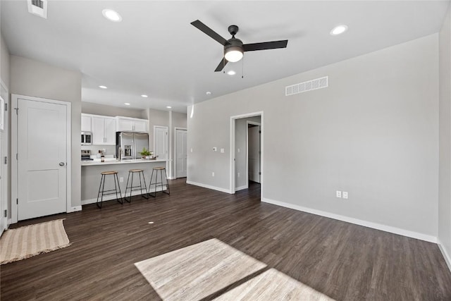 unfurnished living room featuring ceiling fan and dark wood-type flooring