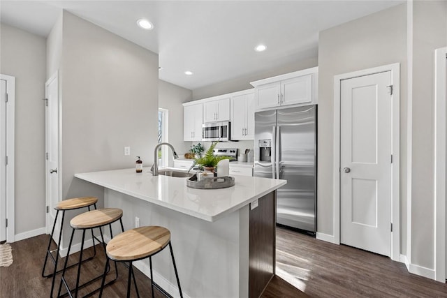 kitchen with sink, appliances with stainless steel finishes, white cabinetry, kitchen peninsula, and a breakfast bar area