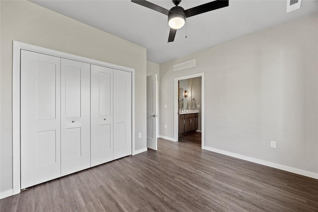 unfurnished bedroom featuring connected bathroom, ceiling fan, a closet, and dark wood-type flooring