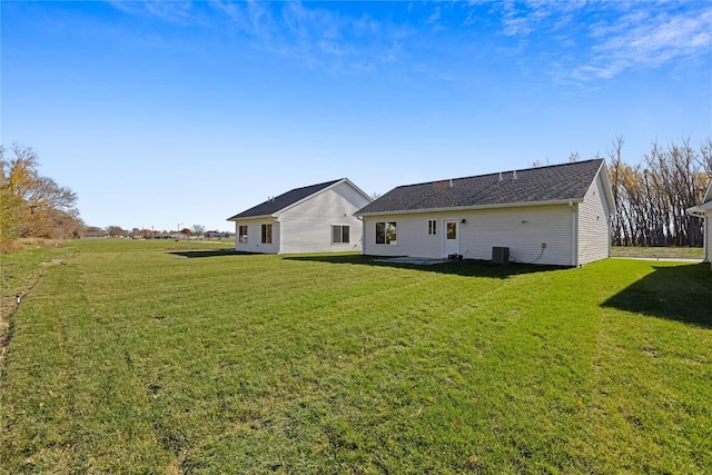 rear view of house with a lawn and central air condition unit