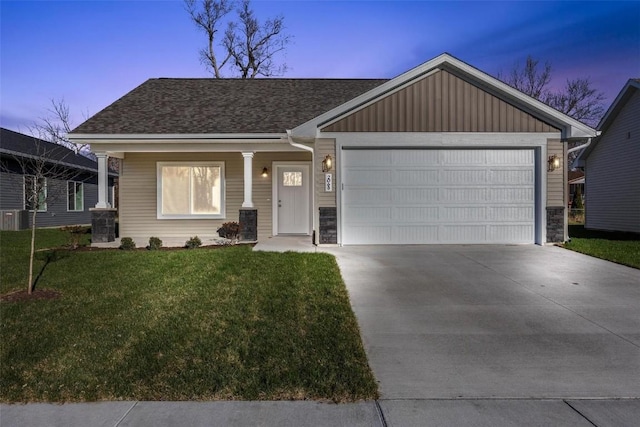 view of front of home with a garage, a yard, and central AC